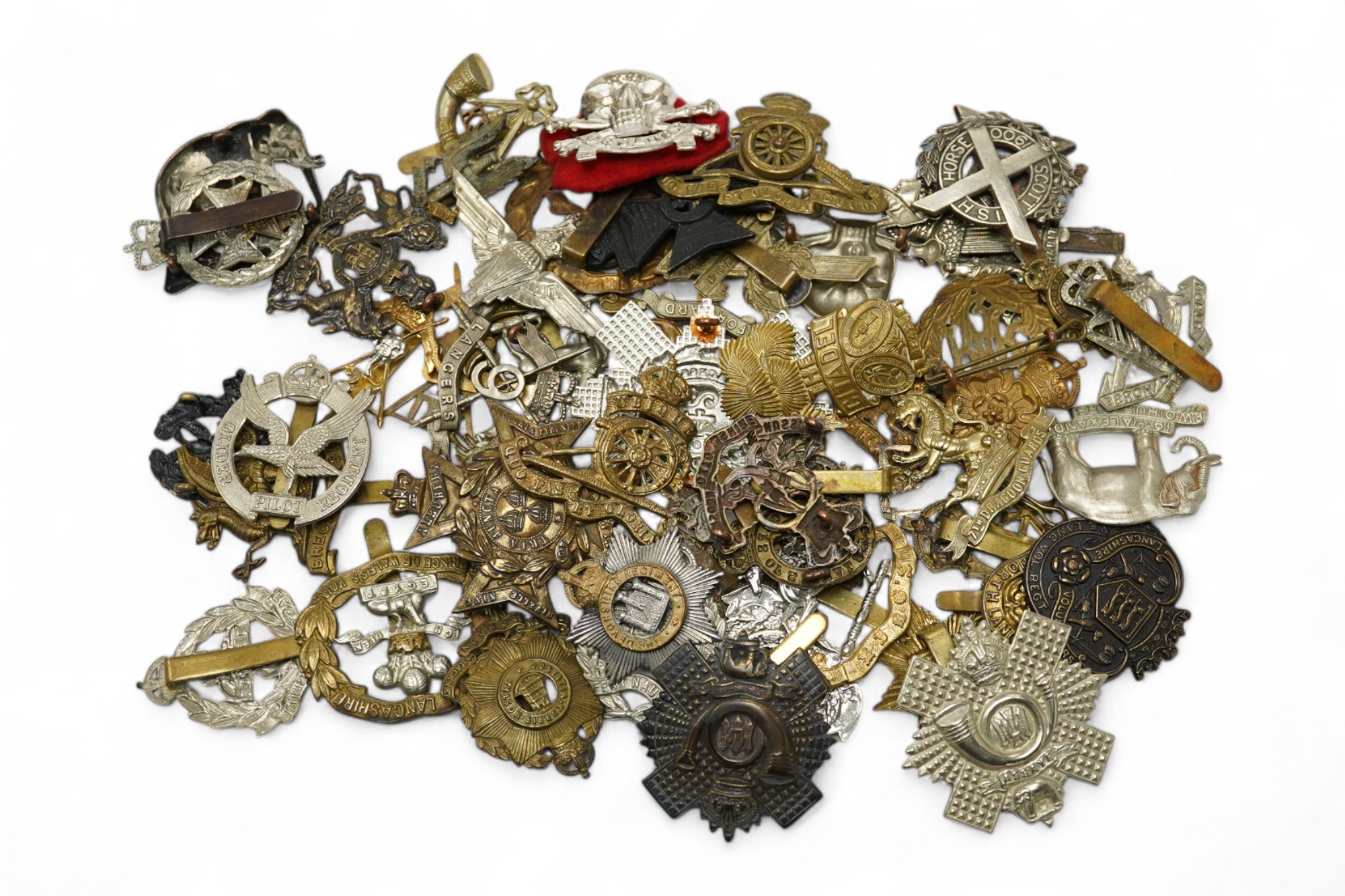 Sixty military cap badges, including; the Brecknockshire Regiment, the Royal Warwickshire Regiment, the South Lancashire Prince of Wales Volunteers, the Royal Artillery, the East Lancashire Regiment, the Glider Pilot Reg